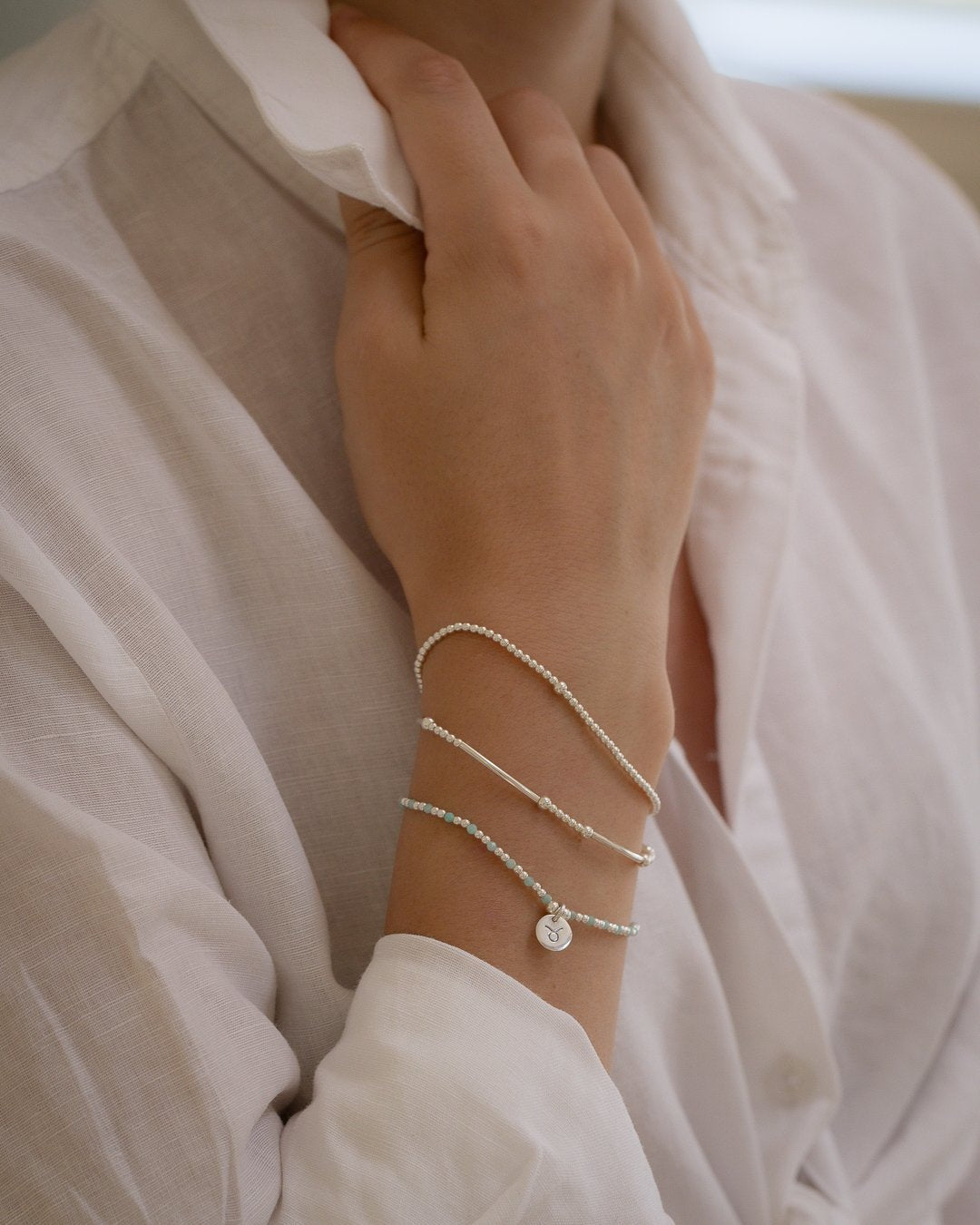 Close up on wrist of Capricorn zodiac charm bracelet stack with silver stretch bracelets by Petals Australia