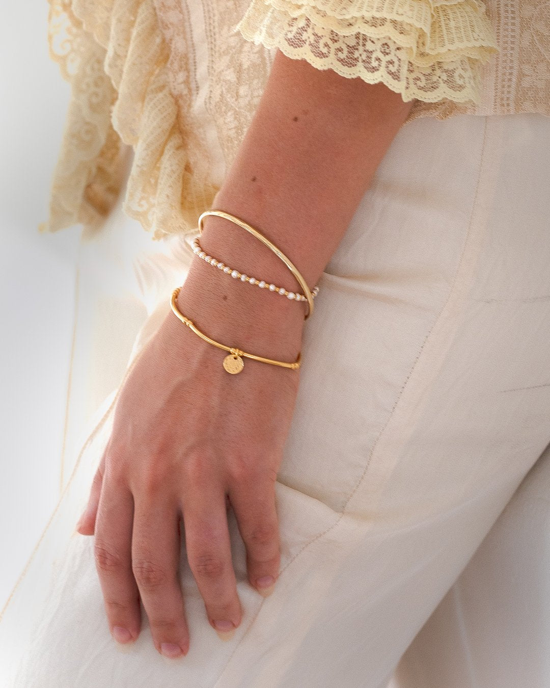Gold Love Letter Stack worn on wrist with personalised initial charm and pearl bracelet