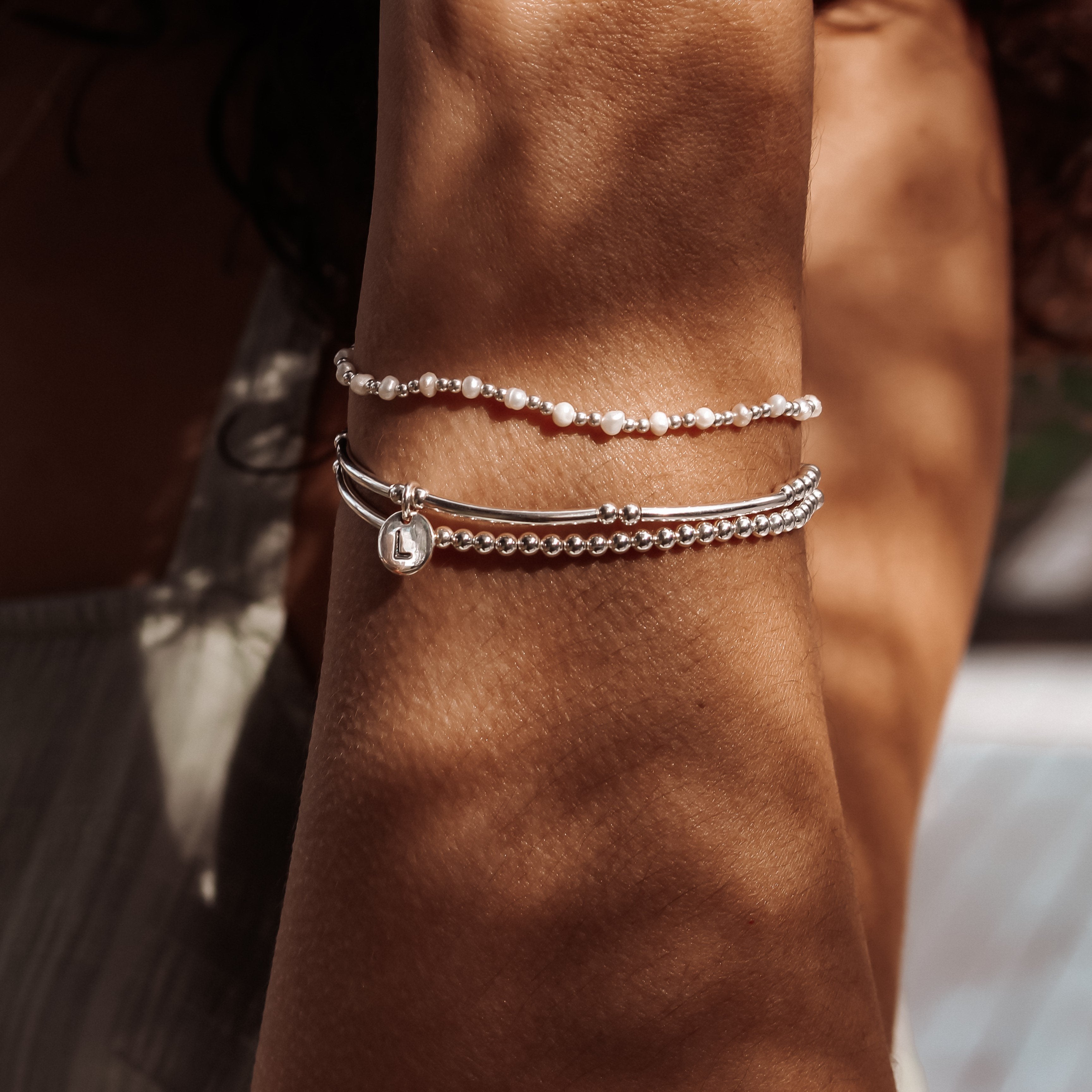 Sterling silver Love Letter Bracelet on wrist layered with other Petals Australia bracelets