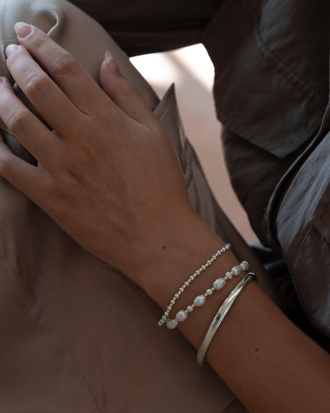 The Secret Stack worn on wrist with sterling silver cuff and pearl bracelet